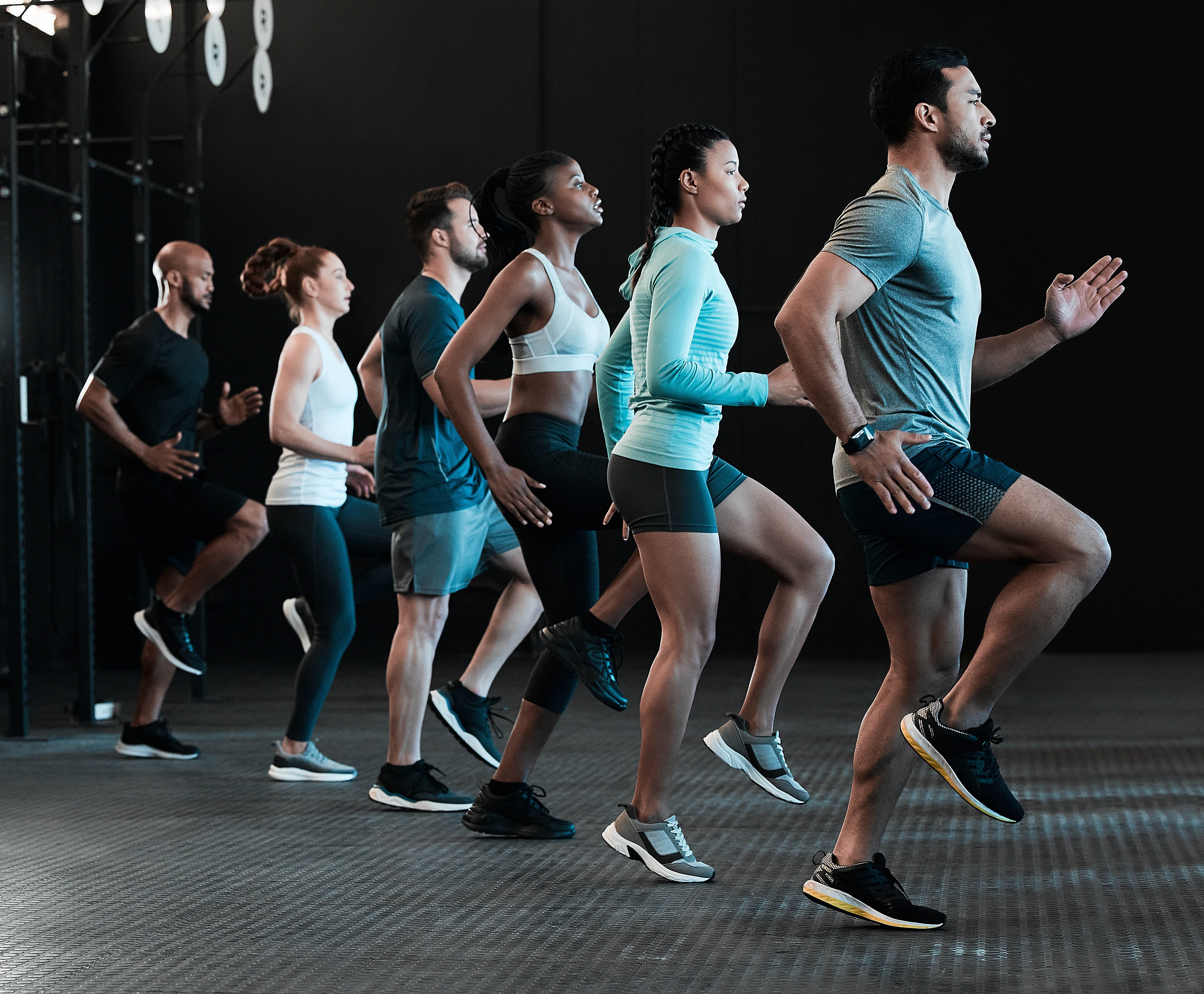 Small group of men and women doing knees up exercise as part of a group workout class Small group of men and women doing knees up exercise as part of a group workout class